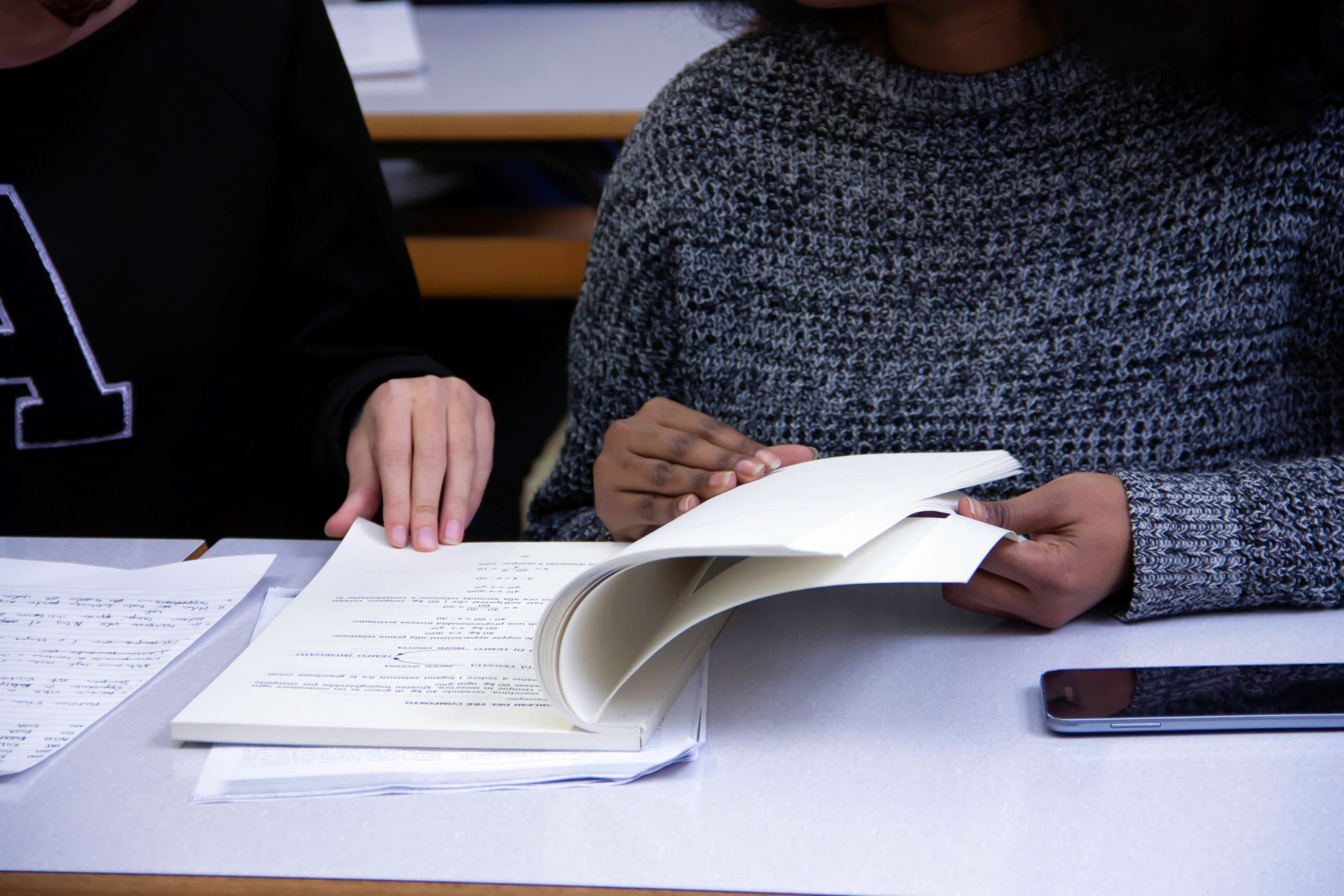 two students studying in library with notebook